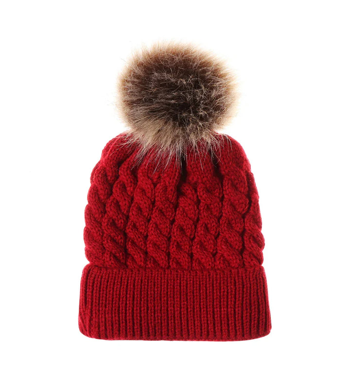 Red knitted winter beanie with cable pattern and large brown faux fur pom pom