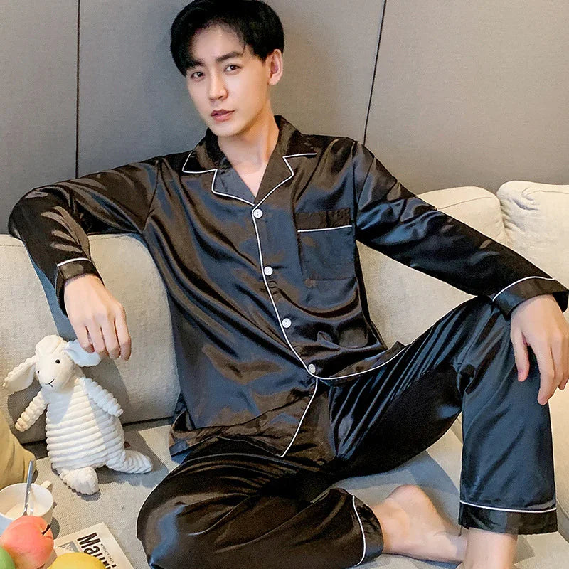 Young man relaxing on sofa wearing black satin pajamas with white piping, holding a stuffed white sheep toy