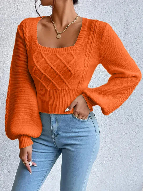 Woman wearing vibrant orange knit sweater with cable knit design and balloon sleeves paired with light blue jeans