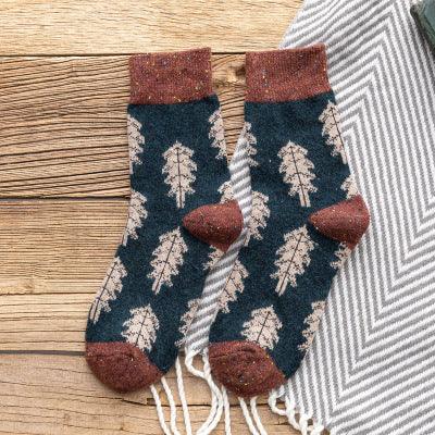 Cozy navy blue socks with white leaf patterns and brown cuffs, heels, and toes on wooden surface