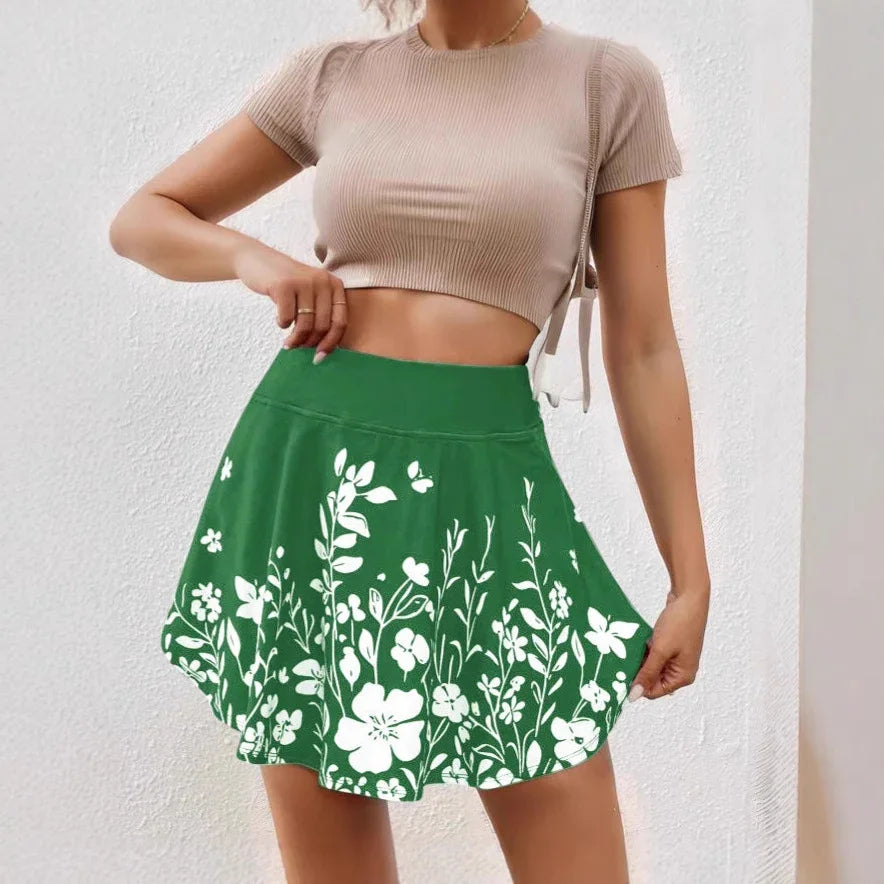 Woman wearing green floral print mini skirt and beige cropped ribbed top against white wall