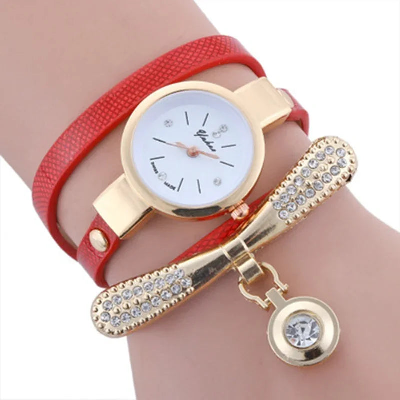 Red leather strap watch with gold case and crystal-studded bow charm bracelet on wrist