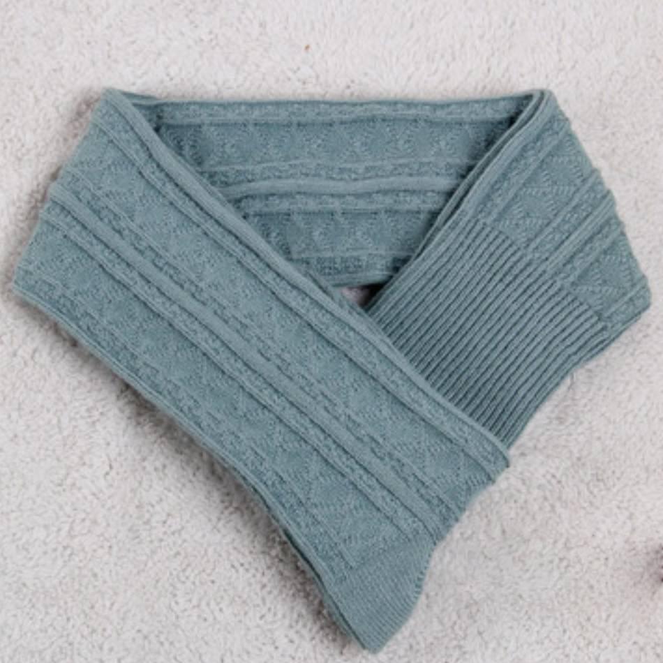Soft teal blue cable knit scarf with ribbed ends displayed on a textured white surface