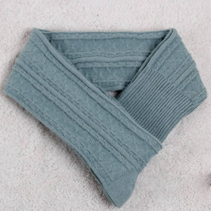 Soft teal blue cable knit scarf with ribbed ends displayed on a textured white surface