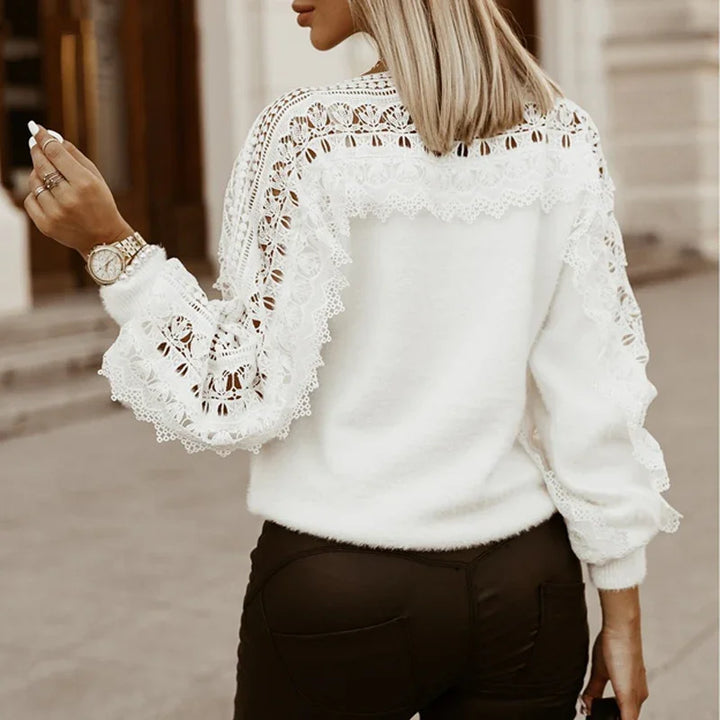 Woman wearing white lace detailed sweater with fringed sleeves and black pants outdoors