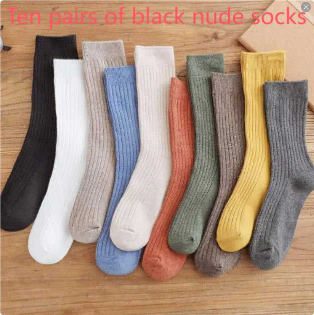 Ten pairs of ribbed knit socks in black, white, beige, blue, cream, rust, green, taupe, yellow, and gray on wood