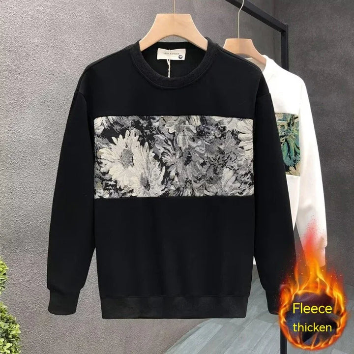 Black fleece sweatshirt with grey floral pattern panel, hanging on wooden hanger against grey background