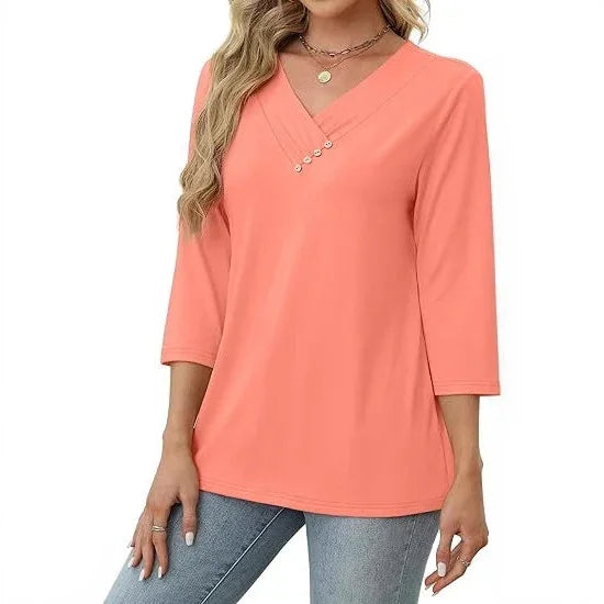 Woman wearing coral 3/4 sleeve V-neck top with decorative buttons, paired with light blue jeans