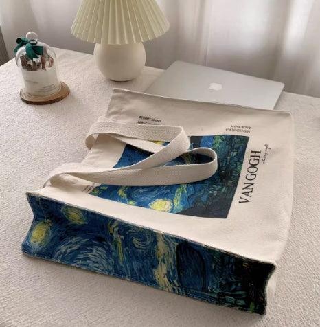 Van Gogh Starry Night canvas tote bag on white desk with lamp and laptop