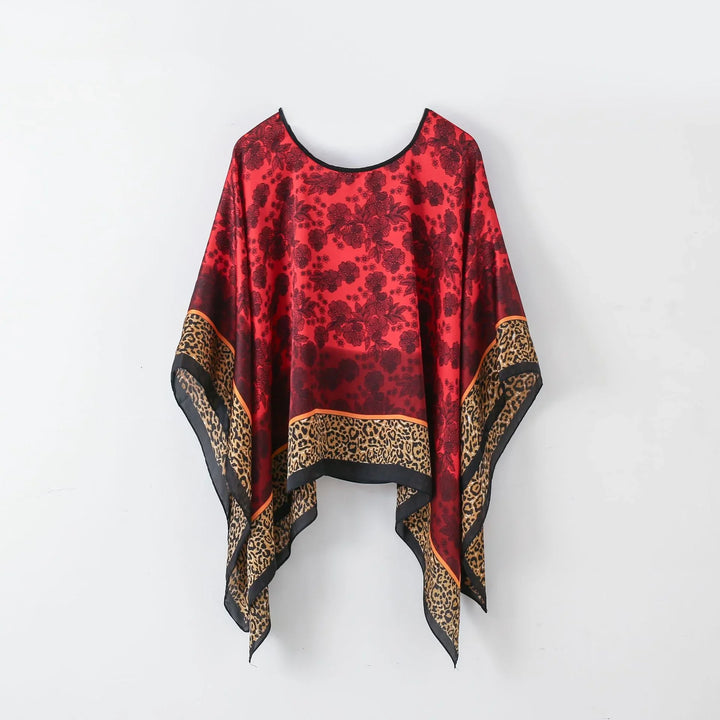 Red and black floral print poncho with leopard print border hanging on white wall