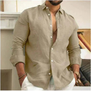 Man wearing casual beige linen button-up shirt with rolled sleeves and white pants indoors