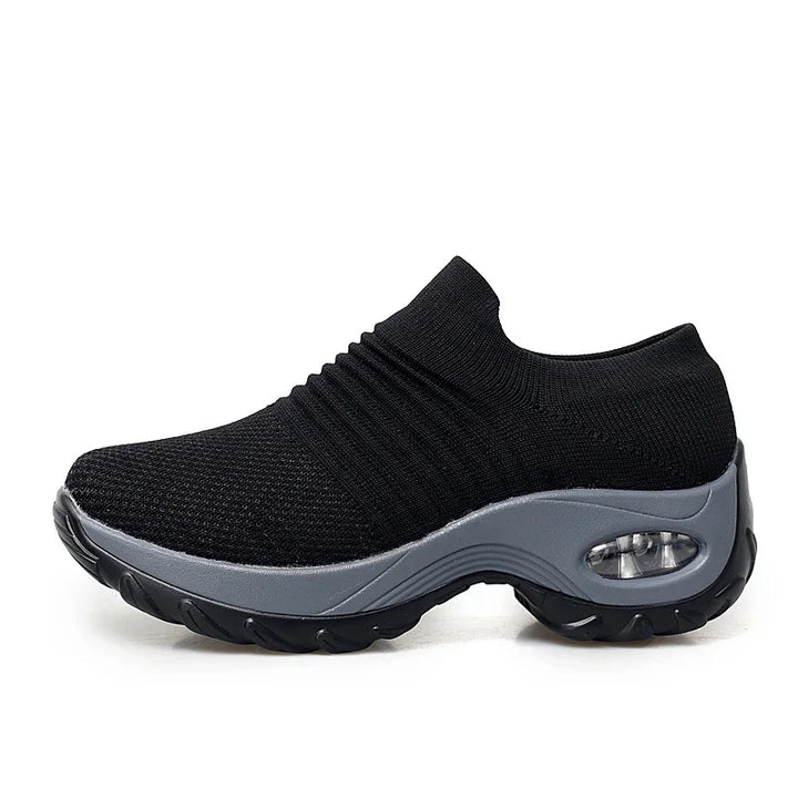 Black slip-on sneaker with knit upper and cushioned gray sole featuring visible air cushion