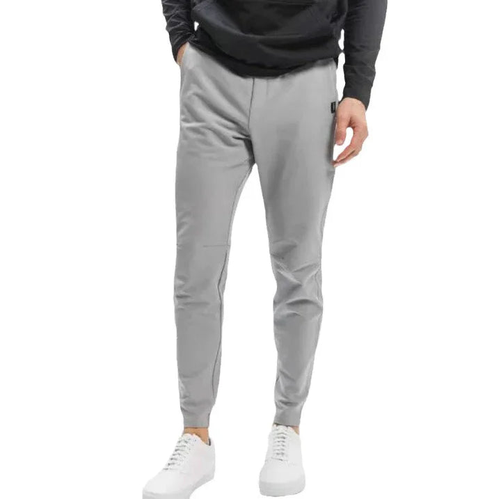 Man wearing light gray slim-fit jogger pants with side pockets and white sneakers