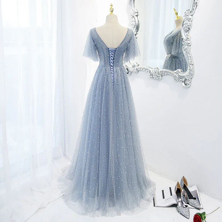 Elegant light blue tulle evening gown with pearl details and lace-up back on mannequin