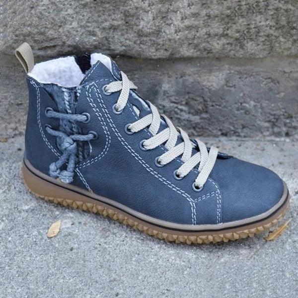 Blue leather high-top sneaker with beige laces, white stitching, and brown rubber sole on concrete surface