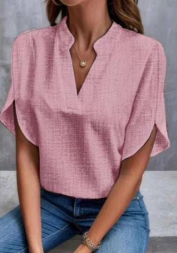 woman wearing textured pink blouse with split sleeves and V-neck paired with blue jeans