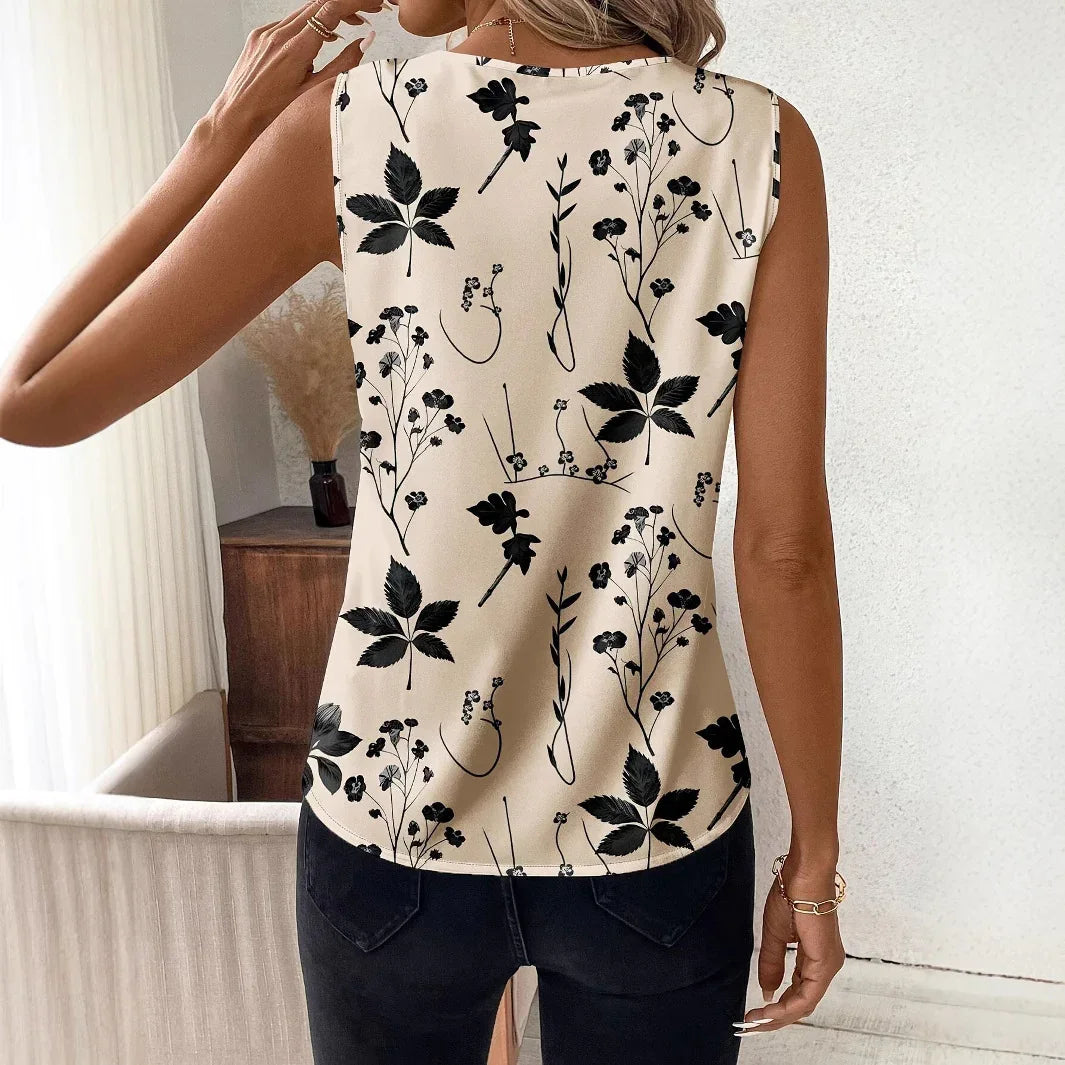 Woman wearing sleeveless beige top with black botanical leaf and flower pattern, paired with black jeans indoors
