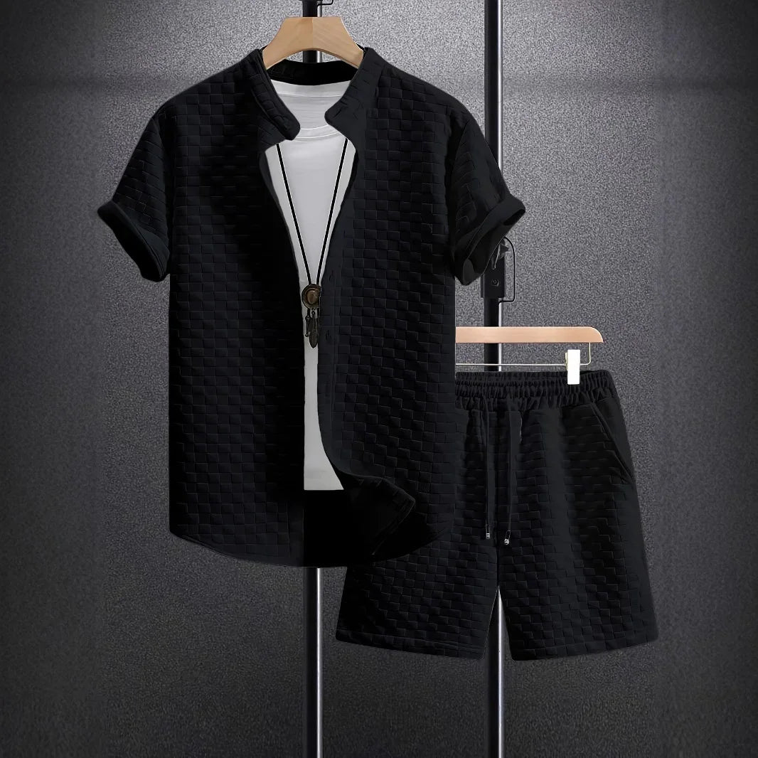 Black short-sleeve jacket and matching shorts with woven texture, displayed with white inner shirt and pendant necklace