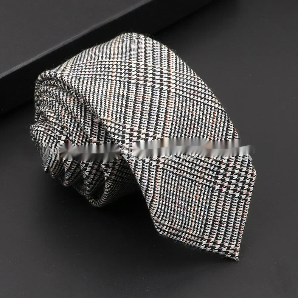 Rolled black and white classic plaid men's necktie on black surface