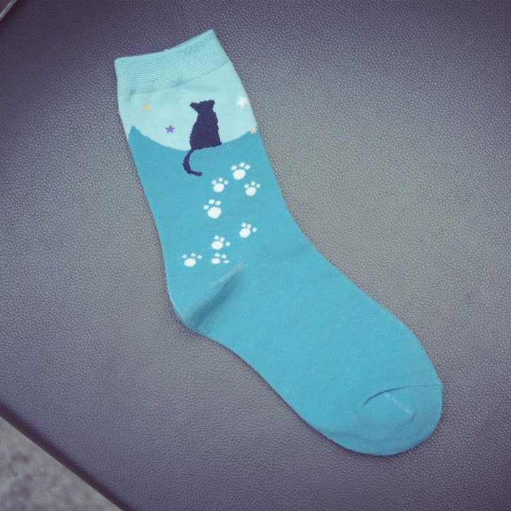 Blue sock with cat silhouette and paw prints design on textured dark background