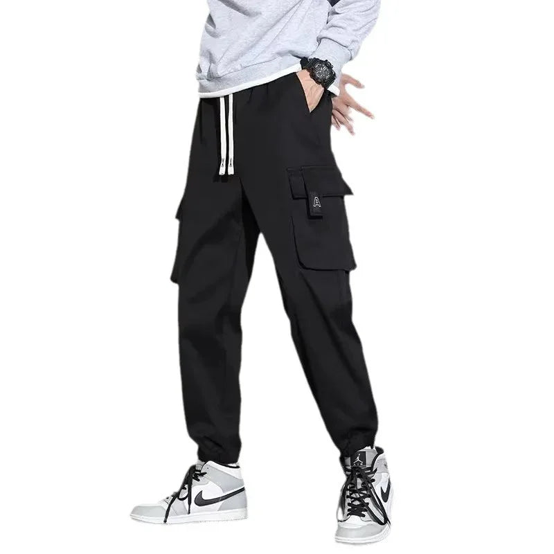 Man wearing black cargo jogger pants with white drawstrings and white Nike sneakers
