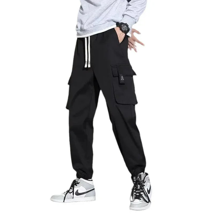 Man wearing black cargo jogger pants with white drawstrings and white Nike sneakers