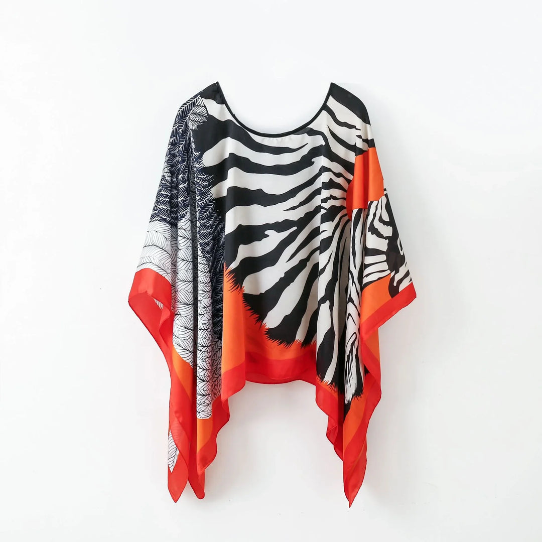 Colorful silk poncho with zebra stripes, orange border, and black leaf pattern on white background