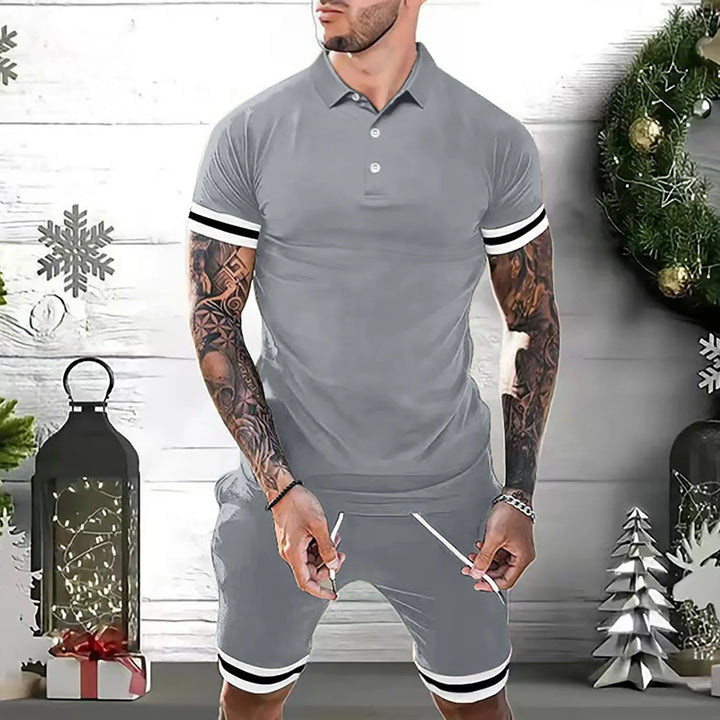 Man wearing gray polo shirt and matching shorts with black and white stripes, standing in festive holiday setting