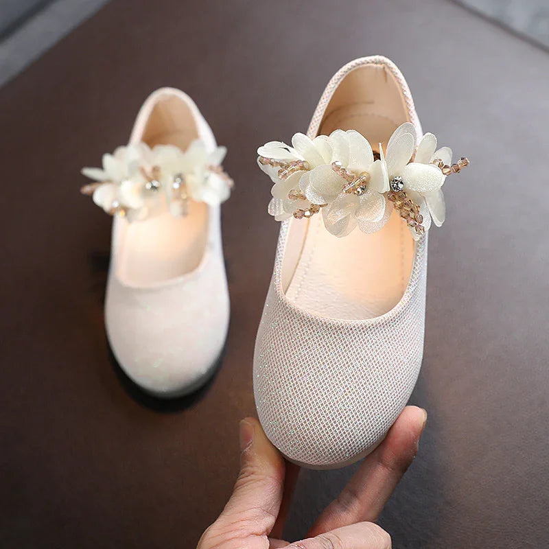 Pair of baby girls' sparkling pink shoes with decorative white flowers and beads