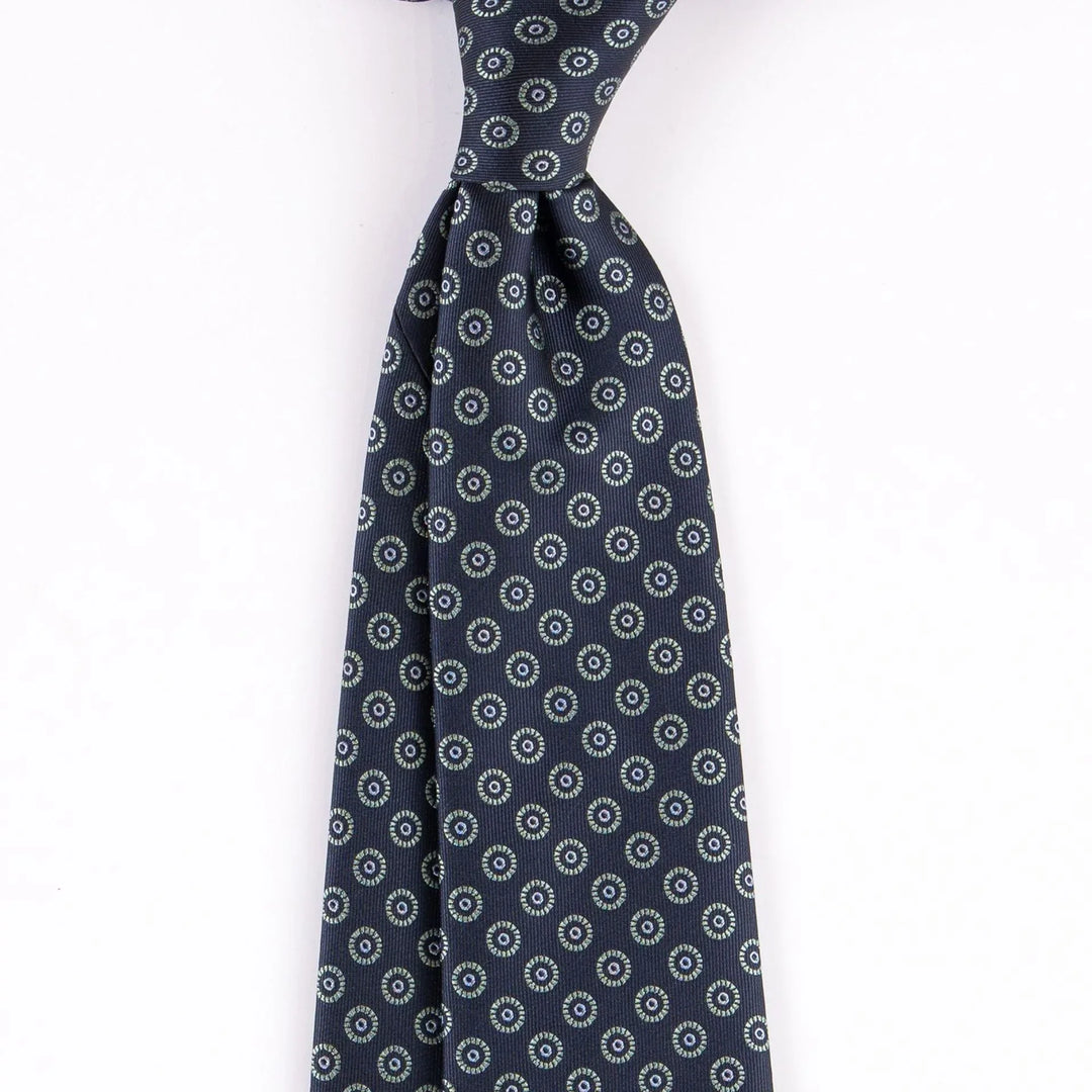 Navy blue silk tie with repeating circular floral pattern detail on white background