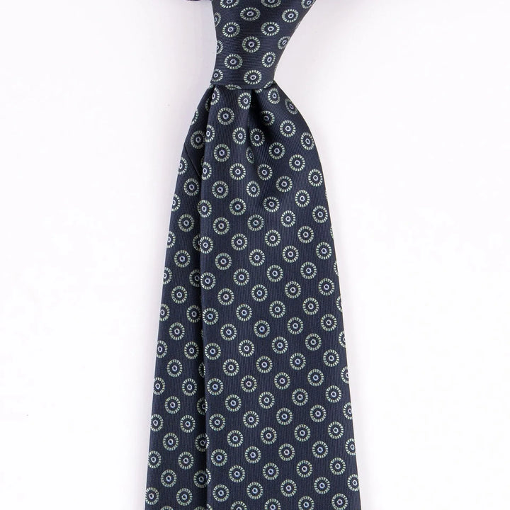 Navy blue silk tie with repeating circular floral pattern detail on white background