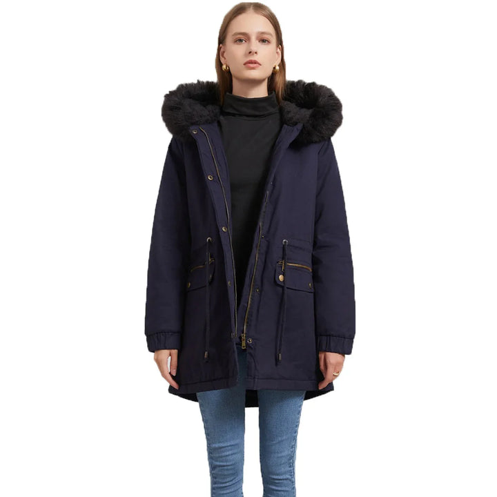 Woman wearing navy parka jacket with black faux fur hood and jeans against white background