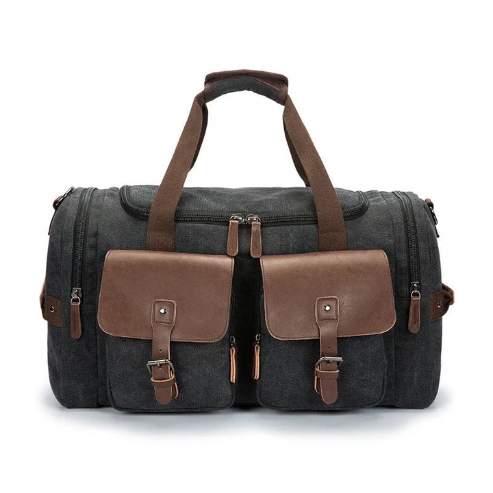 Dark gray canvas duffel bag with brown leather pockets, adjustable straps, and dual handles