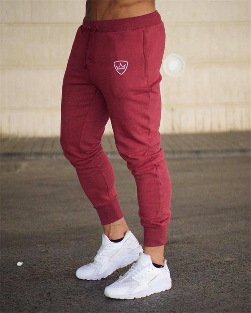 Man wearing fitted maroon jogger pants with white sneakers on urban pavement