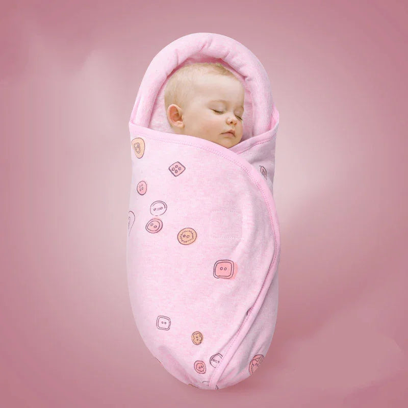 Sleeping baby swaddled in pink blanket with button patterns on pink background