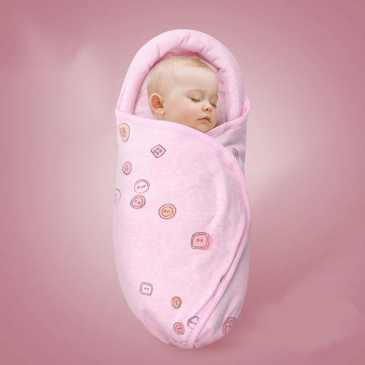 Sleeping baby swaddled in pink blanket with button patterns on pink background