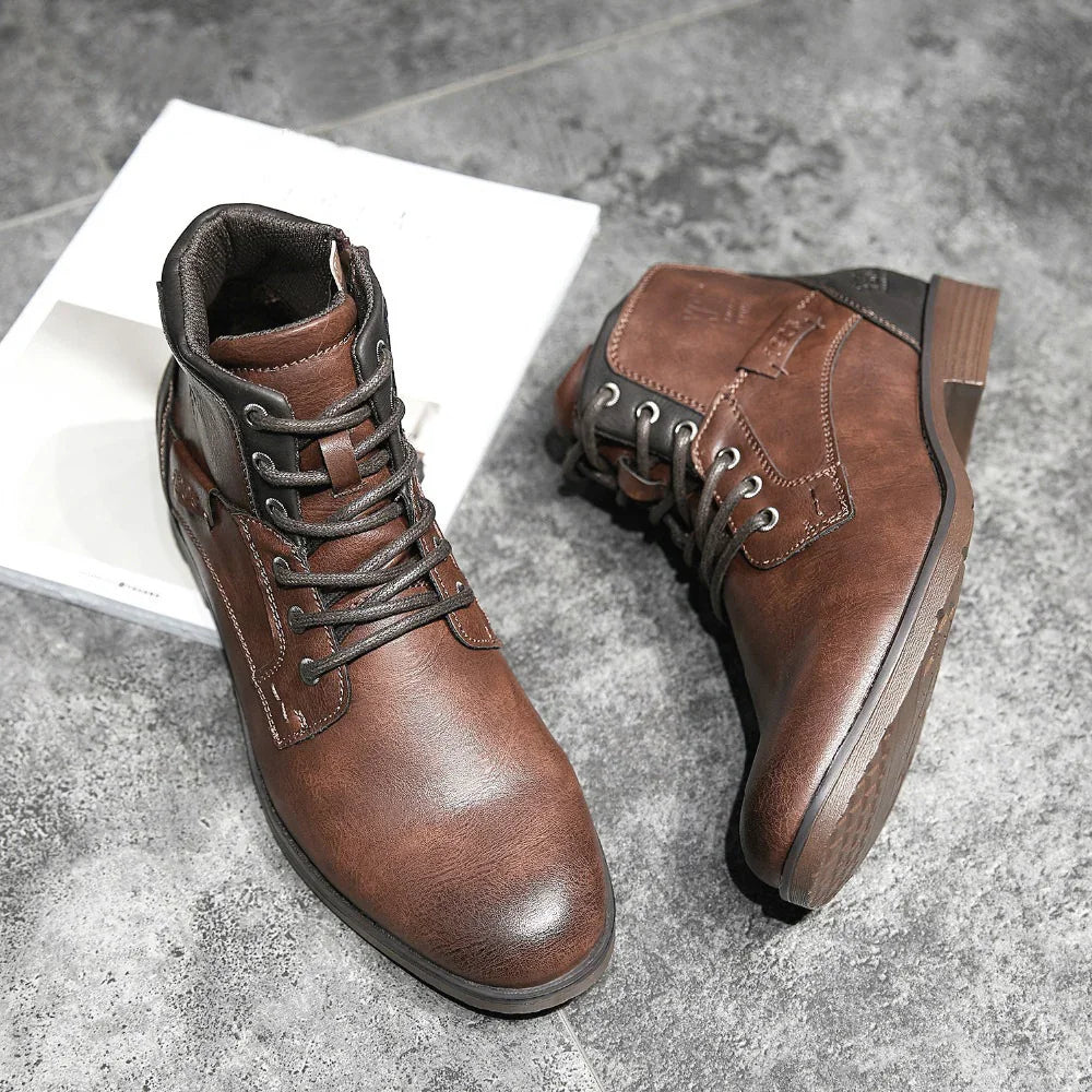 Pair of brown leather lace-up ankle boots on grey tile floor with textured soles