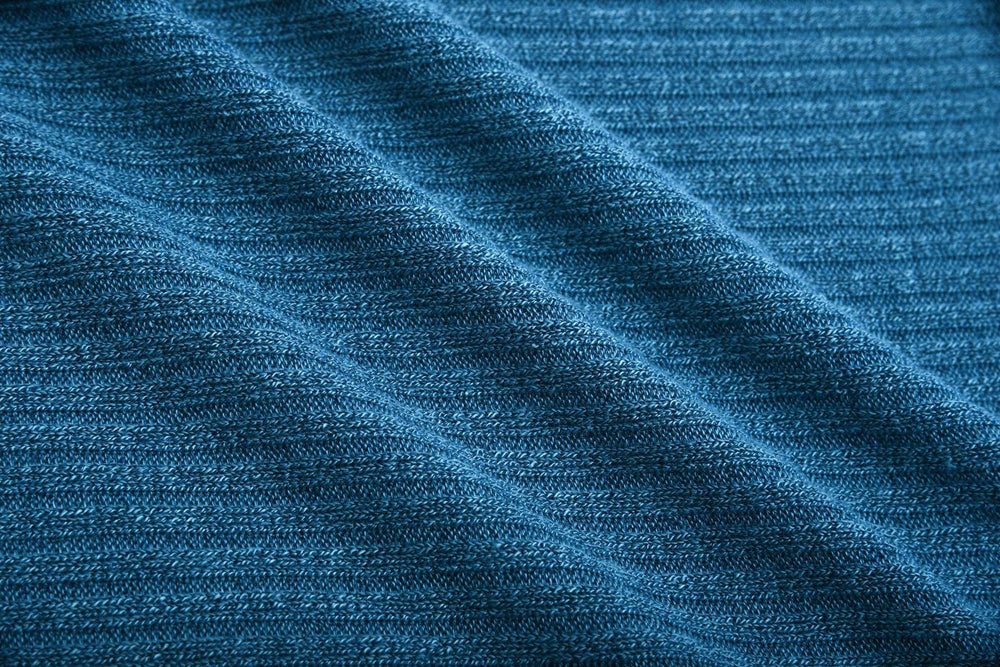 Close-up of textured blue knit fabric with visible detailed stitching pattern