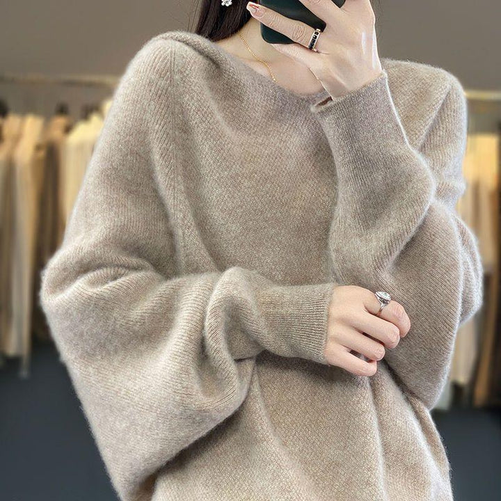 Woman wearing a soft beige oversized sweater with balloon sleeves, holding a phone for a mirror selfie