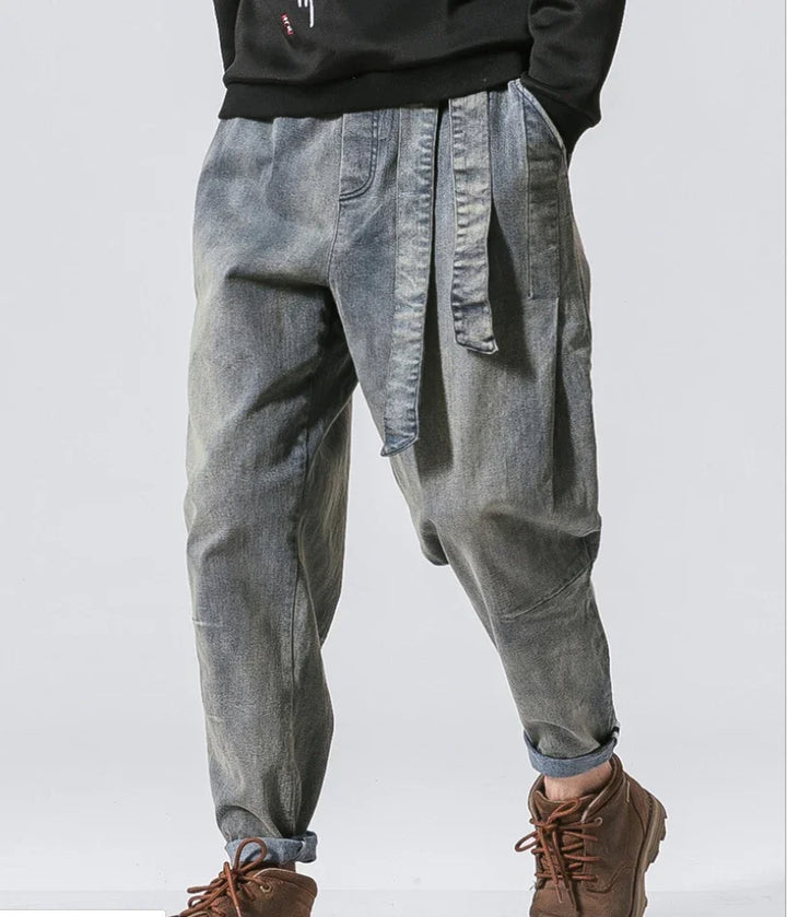 Man wearing gray baggy jeans with attached belt and brown boots, casual fashion style