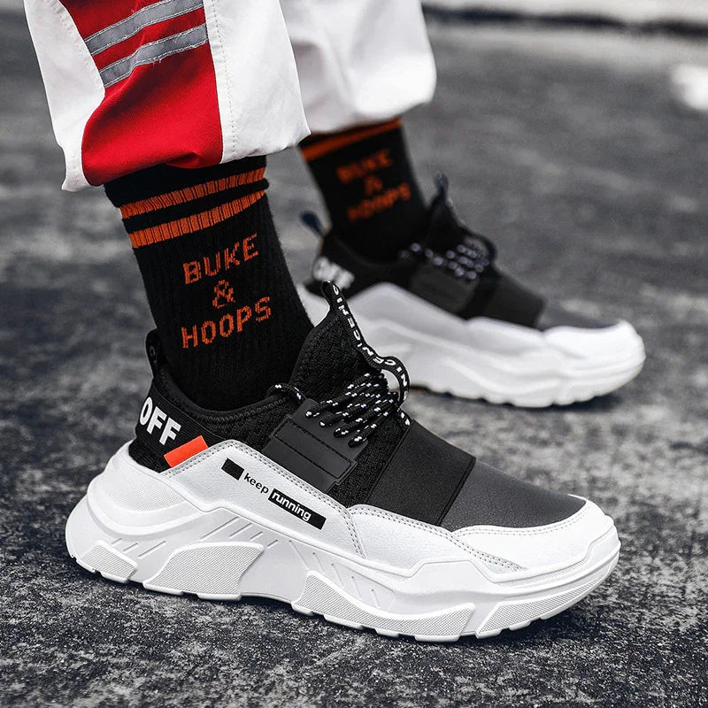 Black and white running shoes with chunky sole, black socks with orange text 'BUKE & HOOPS', streetwear style