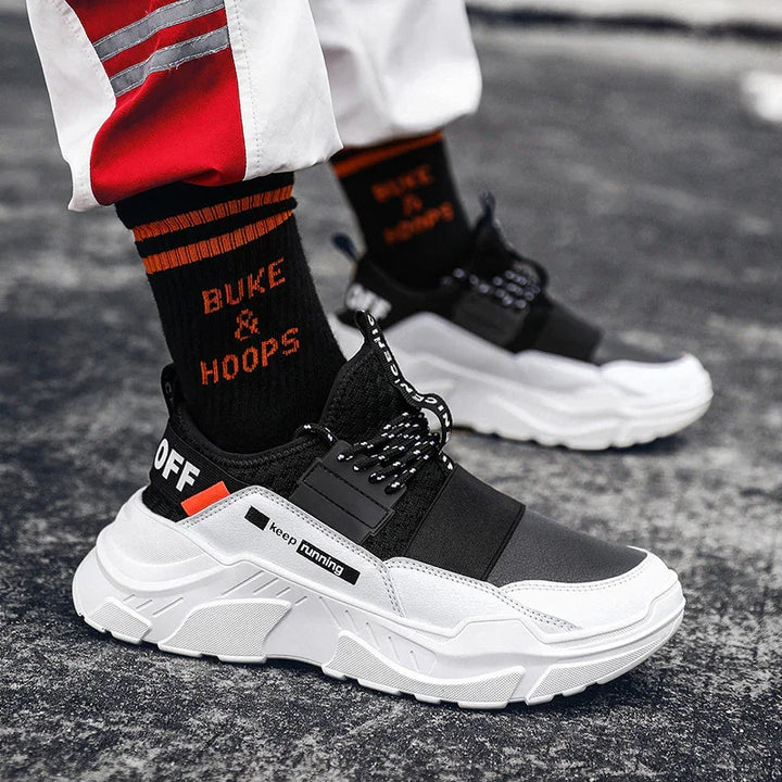 Black and white running shoes with chunky sole, black socks with orange text 'BUKE & HOOPS', streetwear style