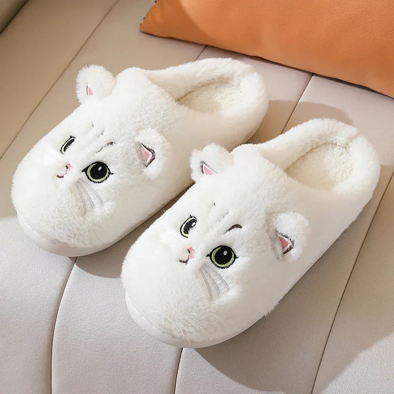 Pair of white fluffy slippers with cute cat face design and ears on a beige surface