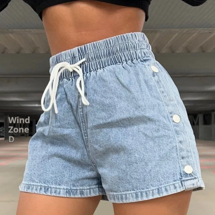Close-up of light blue denim shorts with white buttons and drawstring waist, worn by model