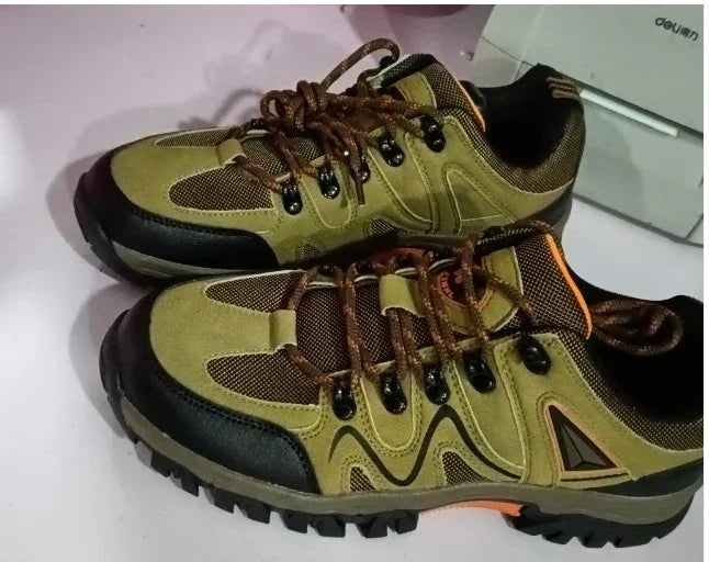 Pair of olive green and black hiking shoes with brown laces on white surface