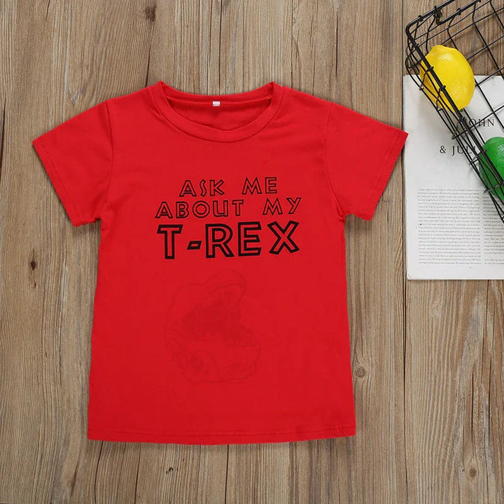 Red kids t-shirt with black text Ask Me About My T-Rex on wooden background