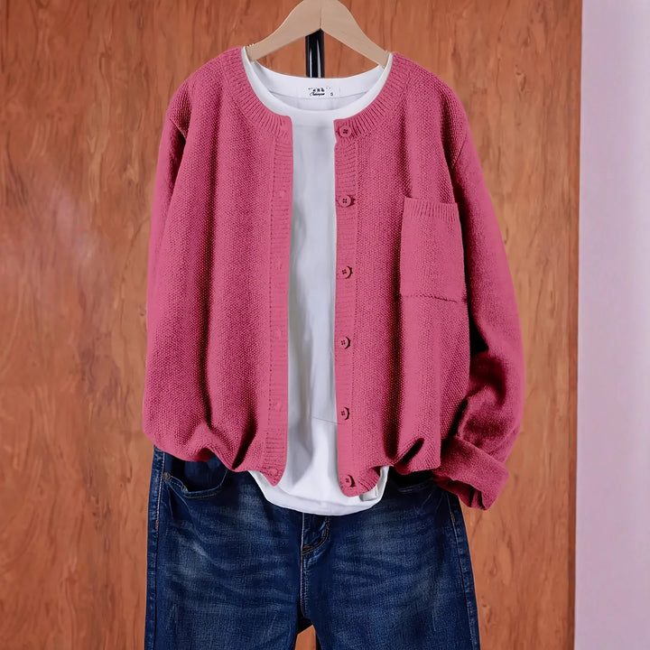 Pink knitted button-up cardigan with pocket over white t-shirt and blue jeans on wooden hanger