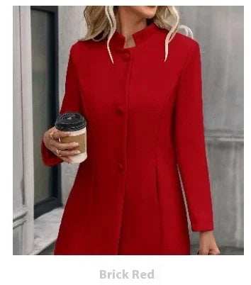 Woman wearing a brick red long coat holding a coffee cup outdoors near a building