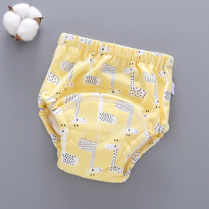 Yellow baby training pants with white and black giraffe prints on gray background