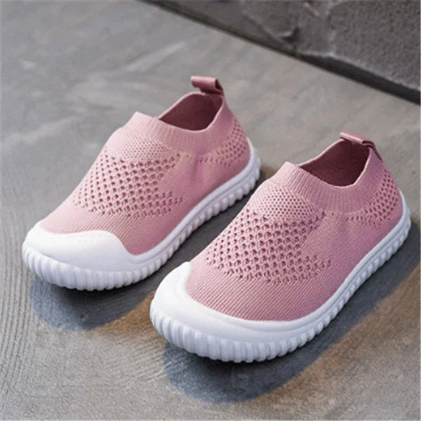 Light pink knit slip-on sneakers with breathable mesh design and white flexible soles on gray surface